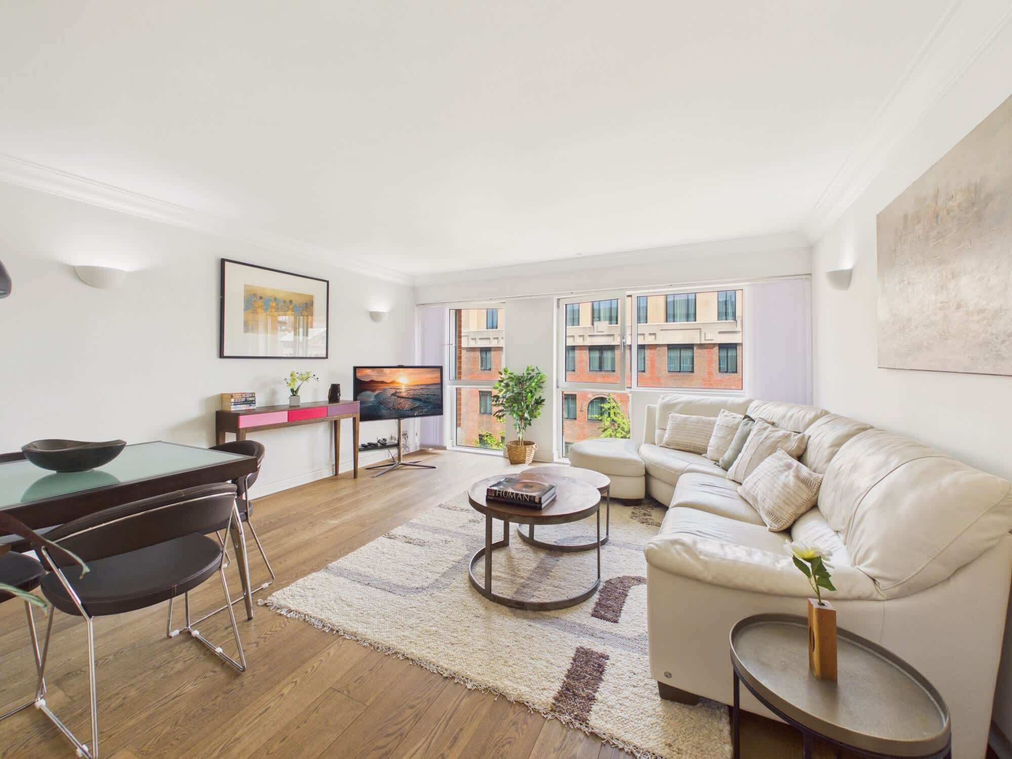 A modern living room with a dining area, a sofa, a coffee table, and a TV.