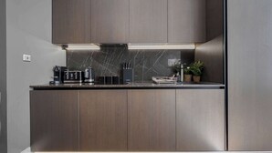 Una cocina moderna con armarios de madera oscura, salpicadero de mármol y campana extractora empotrada.