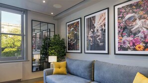 A modern living room with a grey sofa, yellow cushions, and framed artwork on the wall. - The Bloomsbury - by Frankie (London)