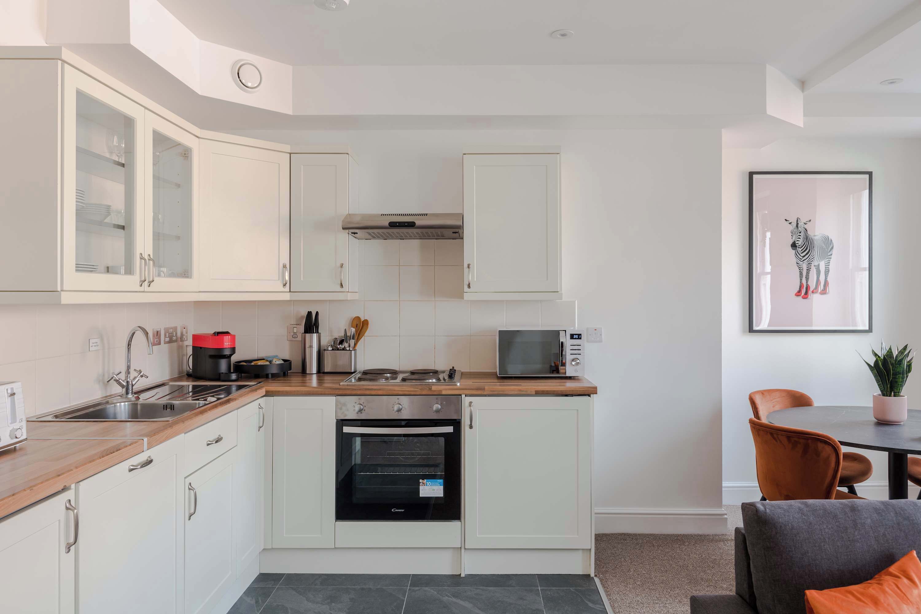 A modern kitchen with white cabinets, a microwave, a stove, and a sink.
