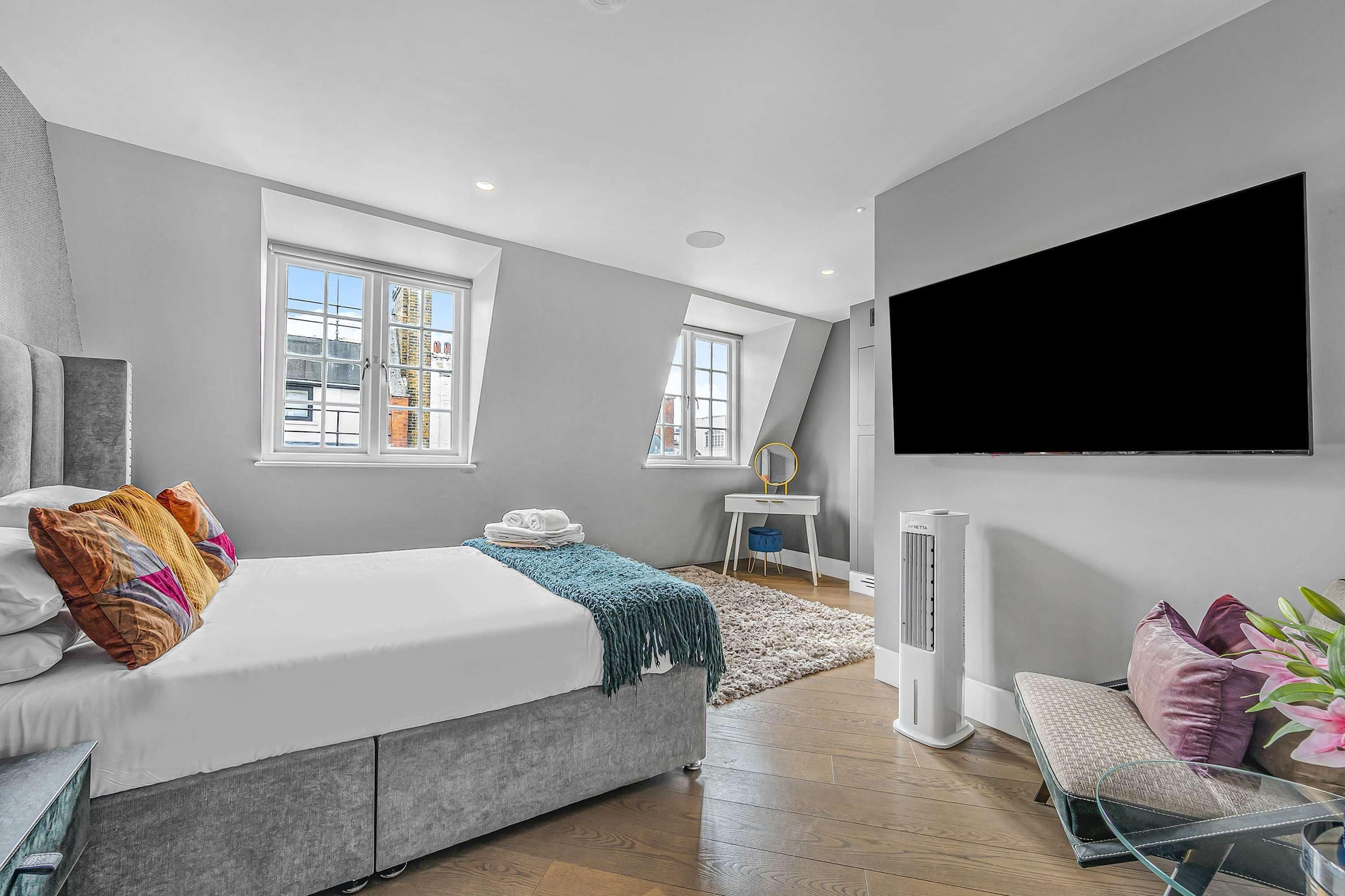 A modern bedroom with a bed, bedside table, TV, and a radiator.