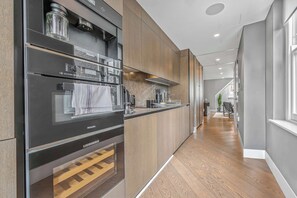 A modern kitchen with built-in appliances, a wooden countertop, and a wooden floor. - The Story Penthouse - Soho - by Frankie (London)