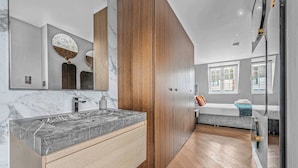 Een moderne badkamer met een marmeren wastafel, houten opbergmeubel en een grote spiegel.