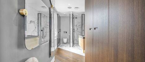 Un baño moderno con tocador de mármol, suelo de madera y cabina de ducha de vidrio.