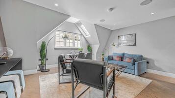 Een modern loft appartement met een eethoek, een blauwe bank en een dakraam.
