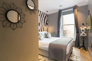 A bedroom with a bed, a large mirror, a radiator, and a window with curtains. - The Chambers - Covent Garden - by Frankie (London)