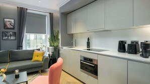 Una cocina moderna con electrodomésticos integrados, un sofá gris y una cafetera.