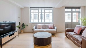 Un salon équipé d’un téléviseur, de deux canapés, d’une table basse et de grandes fenêtres.