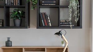 Une bibliothèque remplie de livres, une plante en pot et une lampe de bureau.