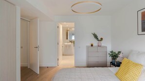 Un dormitorio con cama, mesita de noche, cómoda y lámpara colgante.