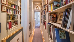 Ein enger Flur mit Bücherregalen an beiden Seiten, der zu einer Tür am Ende führt.
