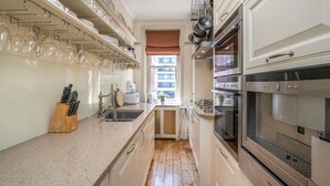 Eine Küche mit weißen Schränken, Edelstahlgeräten und einem Fenster mit Blick.