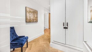 A hallway with a blue chair, a white wardrobe, and a painting on the wall. - Fitzroy Garden - Fitzrovia - by Frankie (London)