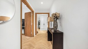 A hallway with a wooden floor, a dark console table with a vase, and a mirror on the wall. - Fitzroy Garden - Fitzrovia - by Frankie (London)