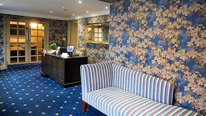Ett väntrum med en randig soffa, en receptionsdisk och en vägg med ett blommönster.