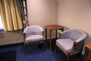 Una habitación con dos sillones a cuadros, una mesita de madera y una alfombra azul con lunares.