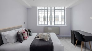 A modern bedroom with a bed, bedside table, and a large window. - The Eyre Suite Two - Farringdon - by Frankie (London)