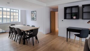 A modern interior with a wooden dining table, black chairs, a black desk, and a potted plant. - The Eyre Suite Two - Farringdon - by Frankie (London)
