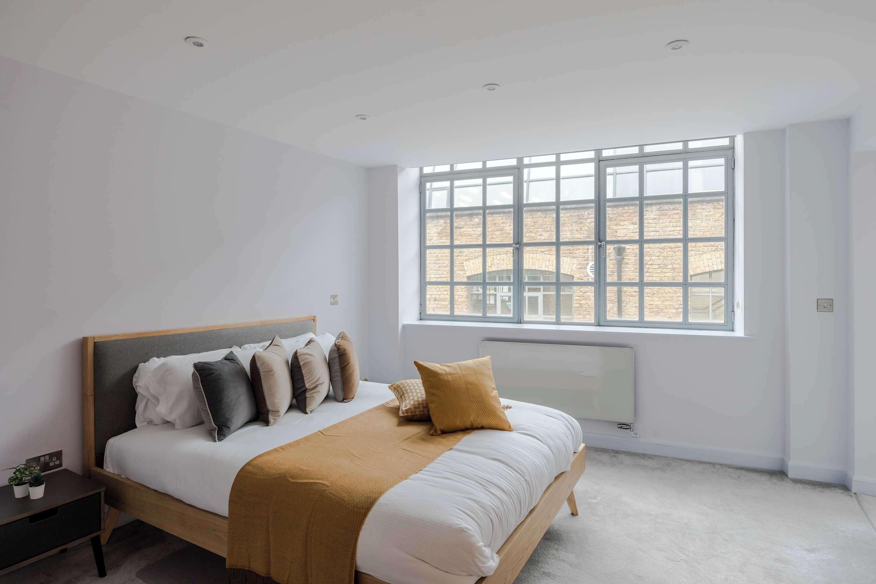 A bedroom with a bed, a window, a radiator, and a nightstand.
