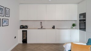 A modern kitchen with white cabinets, a built-in oven, and a coffee machine. - The Tranquil Den - Regent's Park - by Frankie Says (London)