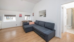 A modern living room with a grey sectional sofa, a dining table with chairs, and a large mirror on the wall. - The Cutesy - Fitzrovia - by Frankie Says (London)
