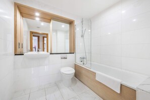 Een moderne badkamer met toilet, wastafel en douche.