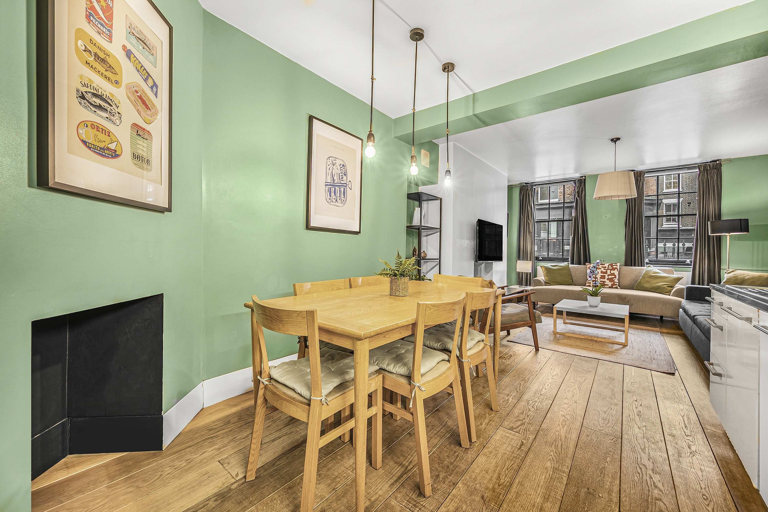 Un área de comedor con una mesa y sillas de madera, un sofá y una chimenea.