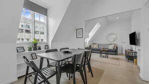 Moderni sisustus, jossa on ruokapöytä, tuoleja, sohva, televisio ja portaikko.