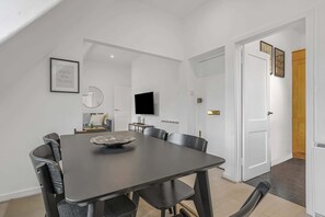 Ein Essbereich mit Tisch, Stühlen, einem Fernseher und einem gerahmten Bild an der Wand.