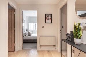 A hallway leading to a bedroom with a bed, a radiator, a framed picture, and a potted plant. - The Eyre Suite Six - Farringdon - by Frankie (London)
