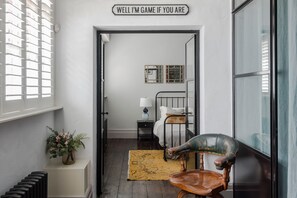 A narrow hallway with a bed, a chair, and a sign reading "WELL I'M GAME IF YOU ARE". - The Dream Factory - Borough - by Frankie Says (London)