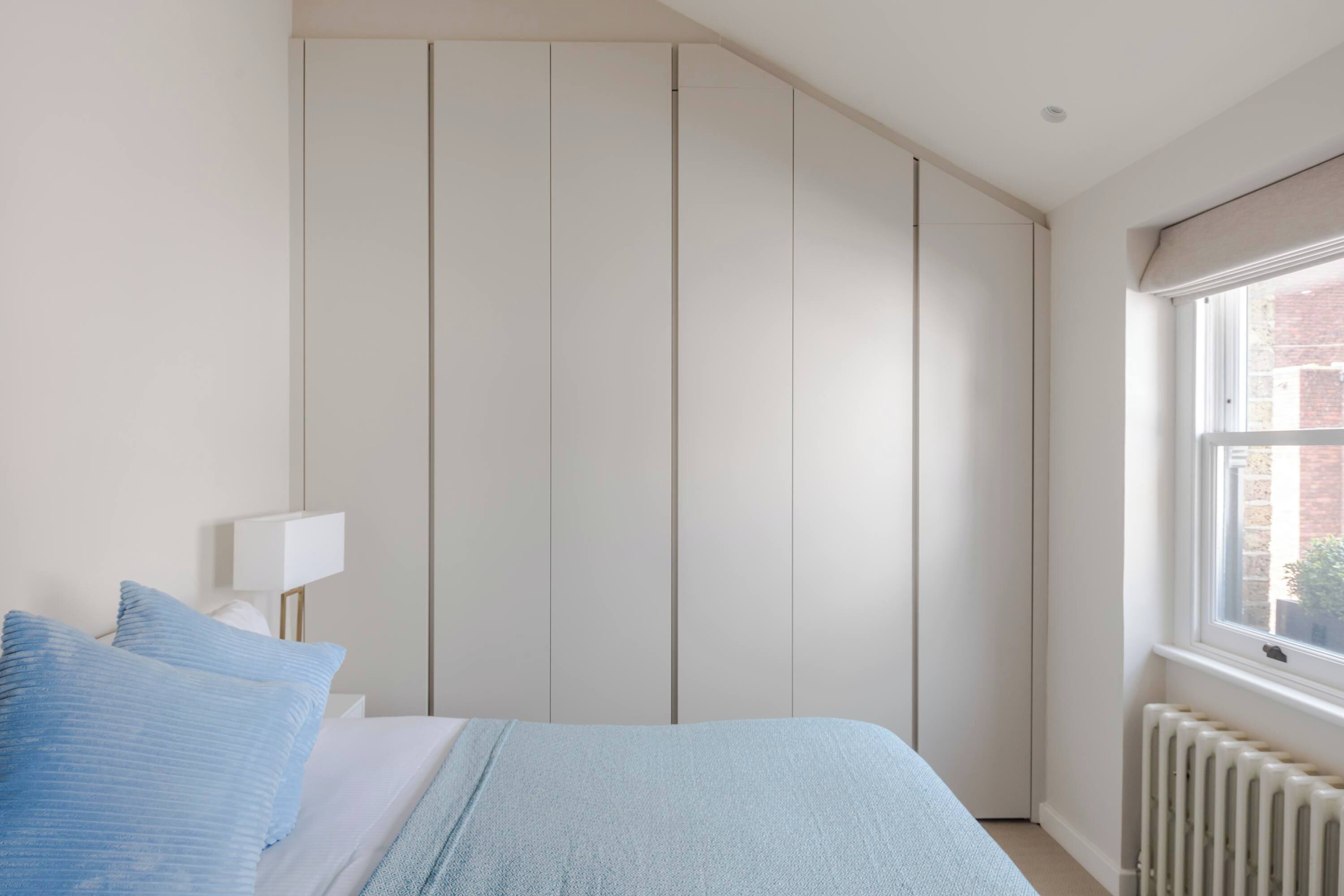 Une chambre à coucher avec un lit, une table de chevet, une fenêtre et un radiateur.