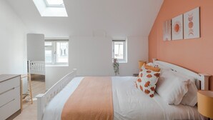 A bedroom with a bed, a desk, and a chair. There are windows and a view of the outside. - Wonderland - Fitzrovia - by Frankie Says (London)