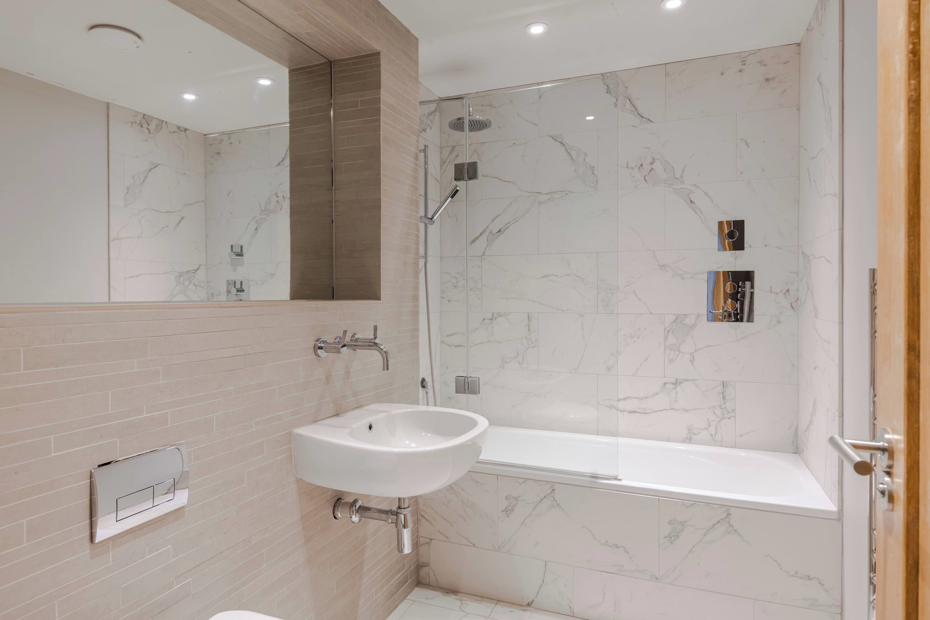 Une salle de bain moderne avec une douche en marbre, un lavabo et un grand miroir.