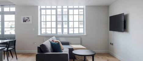 A modern living room with a sofa, a coffee table, and a TV mounted on the wall.