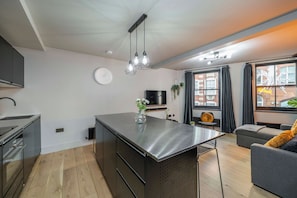 Una cocina moderna con una isla central, un comedor con mesa, un sofá y un televisor.