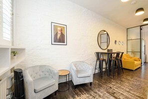 A modern interior with two grey armchairs, a round table, and a yellow sofa. - The Naughty Nautical - Borough - by Frankie Says (London)