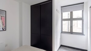 A bedroom with a bed, a black wardrobe, a window with blinds, and a framed picture on the wall. - The Slaycation Crib: Stylish London Retreat By (London)