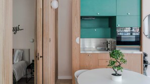 A compact kitchen with teal cabinets, a white countertop, and a small potted plant on a white table. - The Italian Collection - Soho - by Frankie (London)