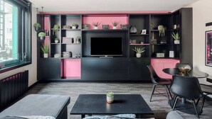Un soggiorno moderno con un mobile TV nero, una parete decorata in rosa e un'ampia finestra.