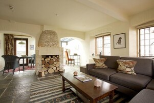 Una sala de estar acogedora con chimenea de piedra, un sofá y una mesa de centro.