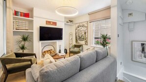 A modern living room with a grey sofa, a flat-screen TV, and a bookshelf. - The Pottter Edition - Covent Garden - by Frankie (London)