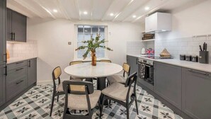 A modern kitchen with a round dining table, grey cabinets, and a patterned floor. - The Pottter Edition - Covent Garden - by Frankie (London)