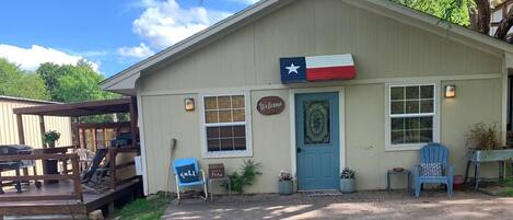 En byggnad med en Texas-flagga, en välkomstskylt och en blå dörr.