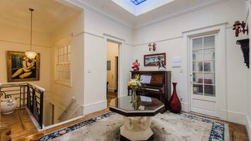 Un hall majestuoso con un piano, una escalera y un techo de vitrales.