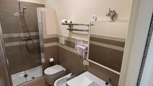 Un bagno con doccia, WC, bidet, lavandino e porta asciugamani.