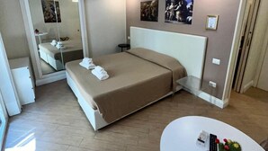 Una camera d'albergo moderna con un letto grande, un tavolino con un cactus e uno specchio.