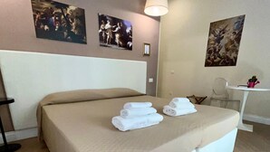 Una camera d'albergo con un letto grande, una scrivania con una sedia e opere d'arte alle pareti.