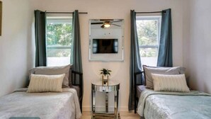 A room with two beds, a ceiling fan, a TV mounted on the wall, and a small table with a plant. - Wynwood Escape
Built for long-term stay (Miami)