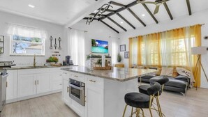 A modern kitchen with white cabinets, a central island, and a dining area with a sofa and bar stools. - Wynwood Escape
Built for long-term stay (Miami)